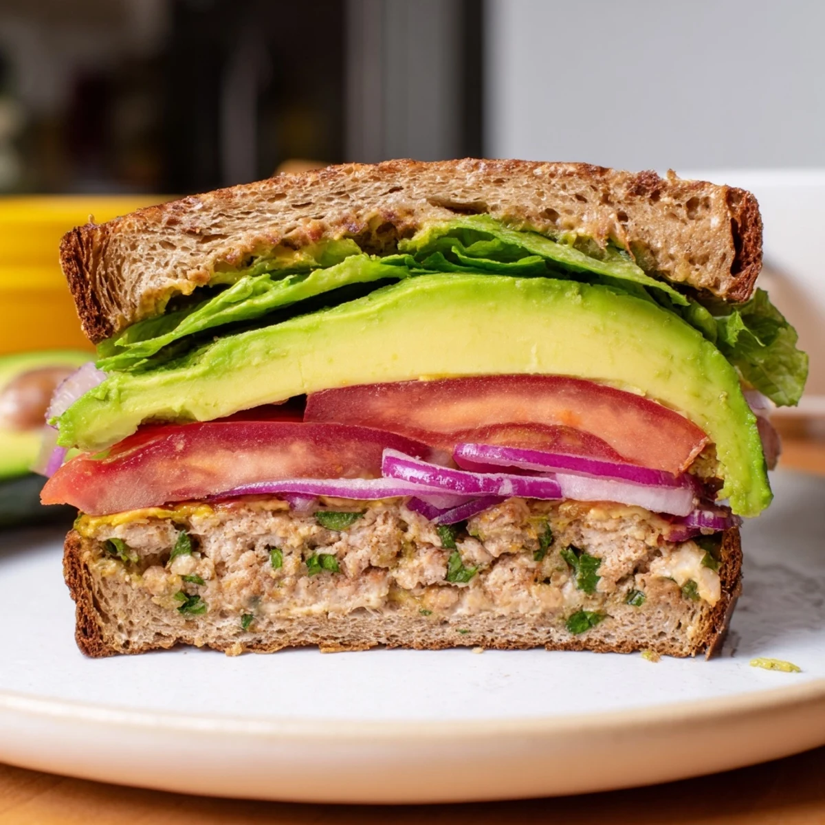 Grilled turkey burger with avocado and toppings, served with a side salad for a healthy meal.
