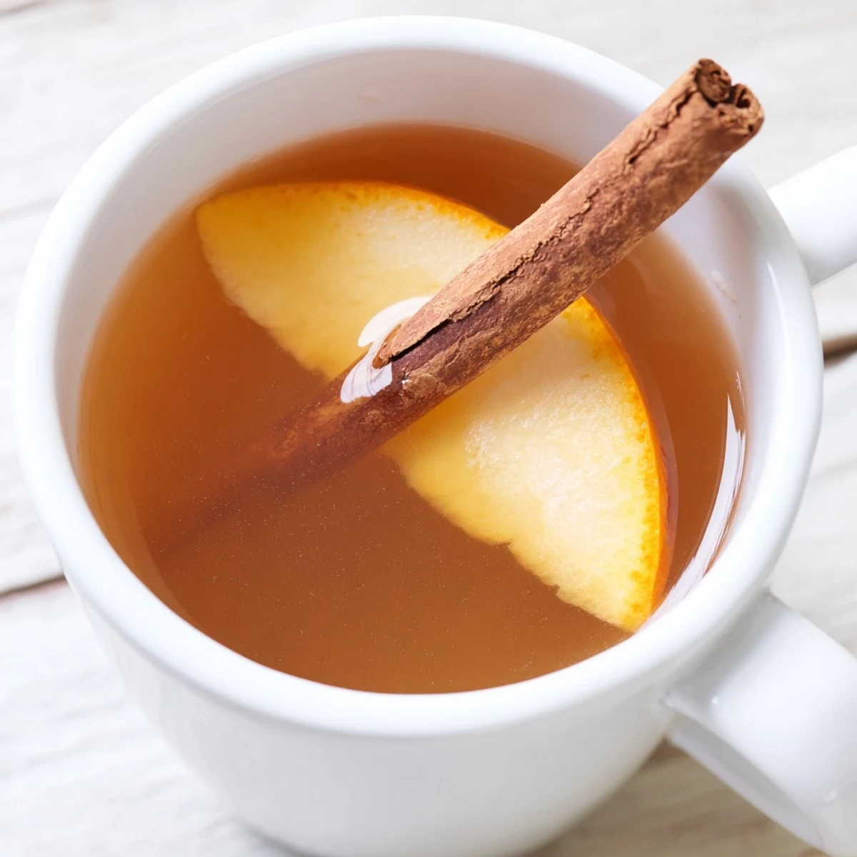 Fragrant spiced hot apple juice with cinnamon steams from a pot, ready to be poured into festive mugs.