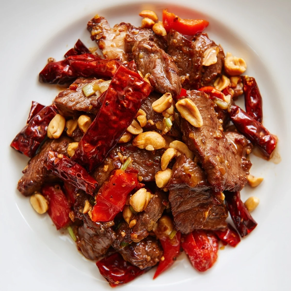 Spicy Szechuan Beef with Peanuts tossed with colorful bell peppers and onions in a glossy, aromatic sauce in a skillet.