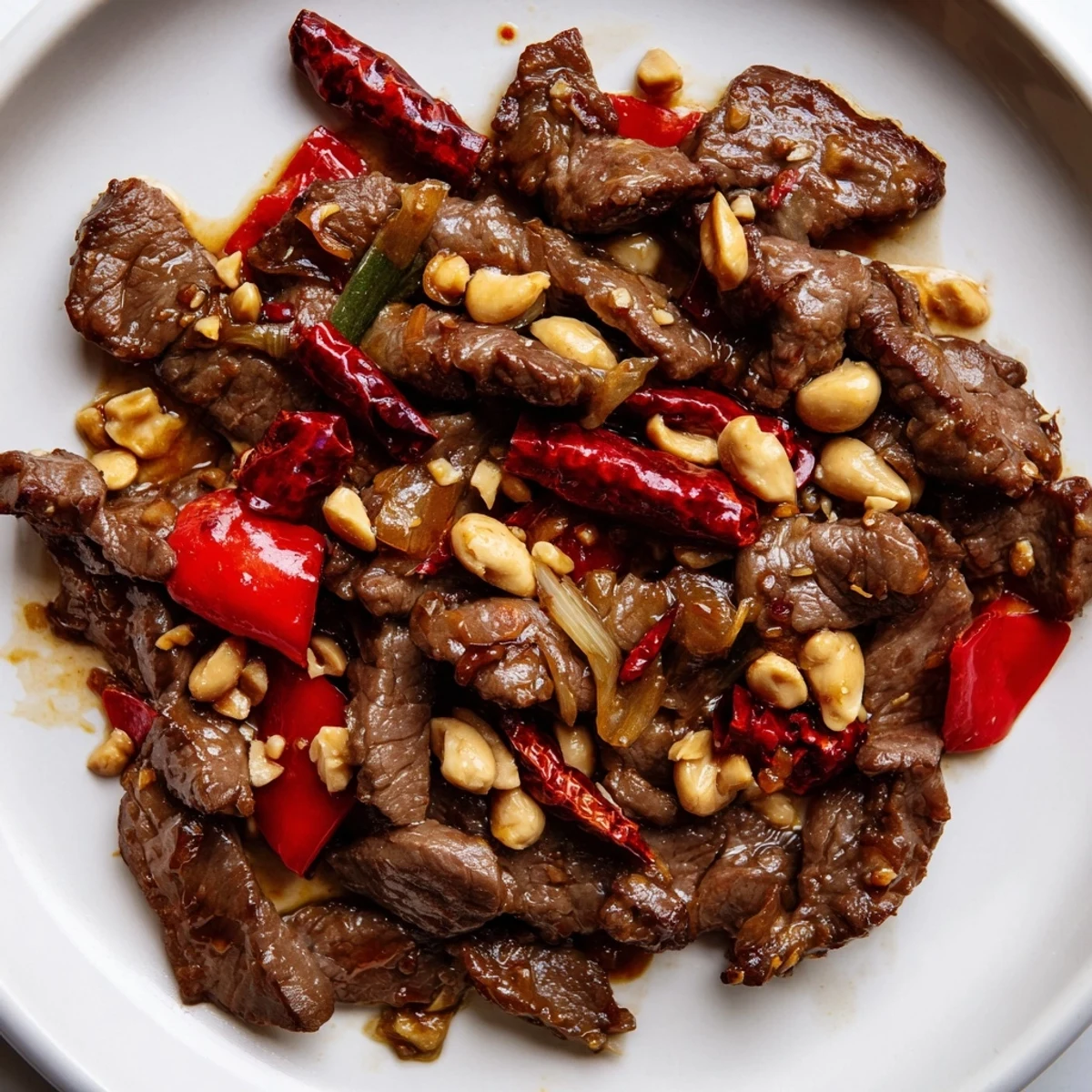 Close-up of tender beef strips and crunchy roasted peanuts mixed with vibrant red peppers in a spicy Szechuan stir-fry.