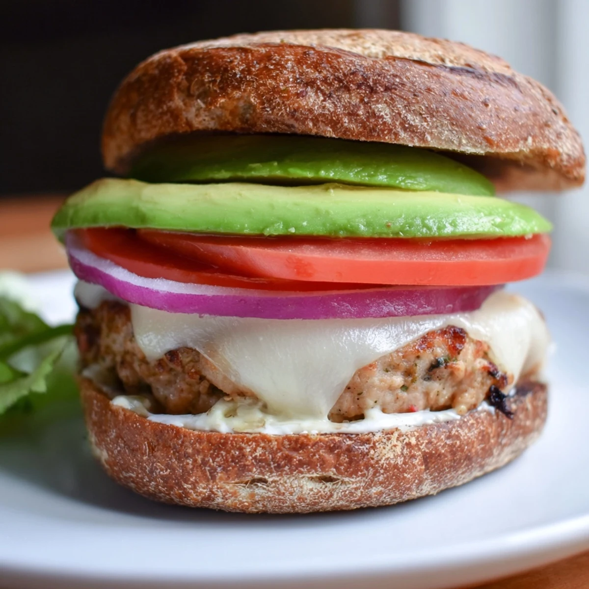 A plated turkey burger with melted Swiss cheese and avocado slices, ready to enjoy with crispy sweet potato fries on the side.