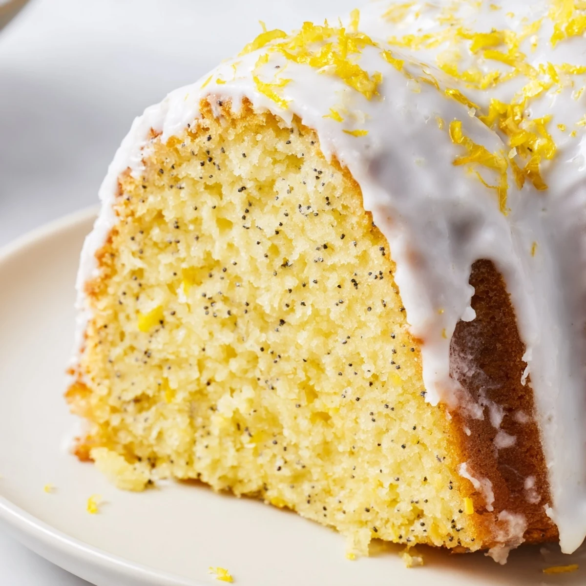 Freshly baked Lemon Poppy Seed Bundt Cake with a shiny, zesty glaze drizzled over the top on a cooling rack.