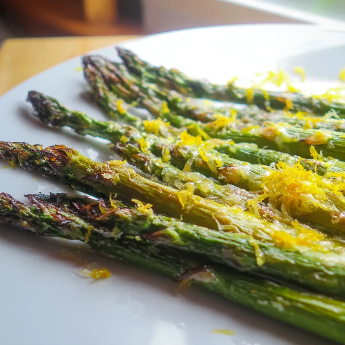 Golden brown roasted asparagus spears topped with fresh Parmesan and lemon wedges, ready to serve as a side dish.