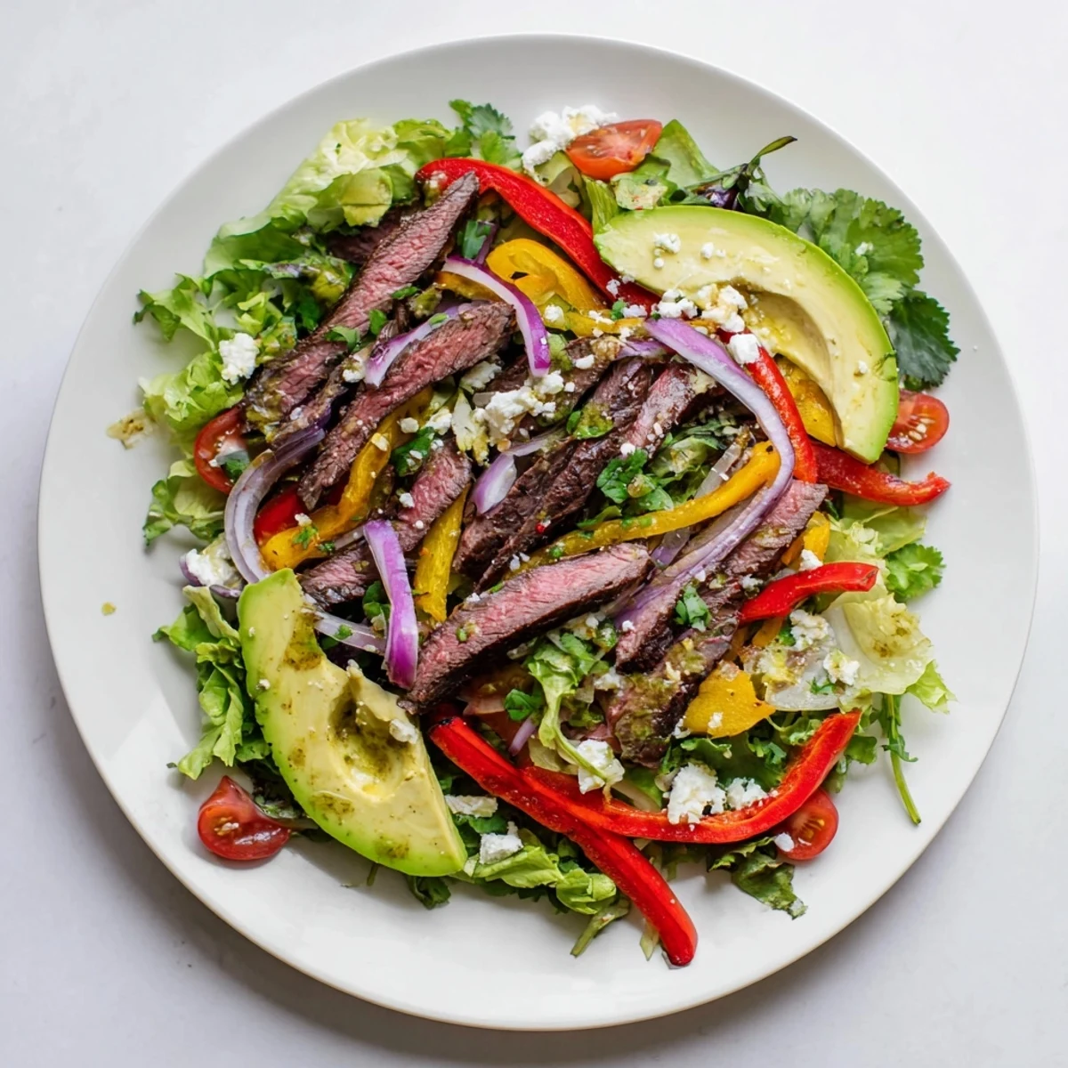 A vibrant Beef Fajita Salad with grilled steak, colorful peppers, and creamy avocado topped with zesty lime vinaigrette.