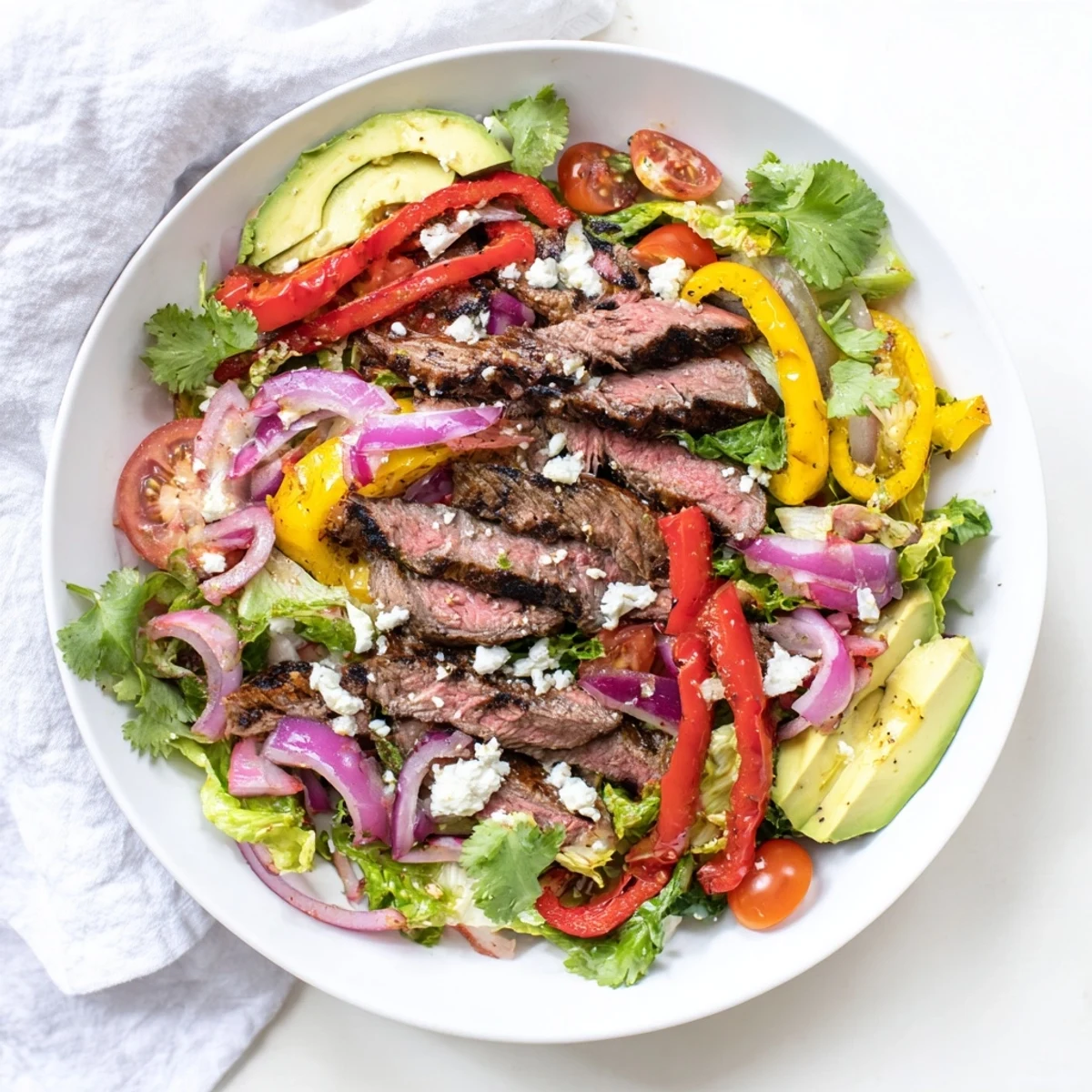 Freshly grilled Beef Fajita Salad arranged on a platter with mixed greens, cherry tomatoes, and cotija cheese.