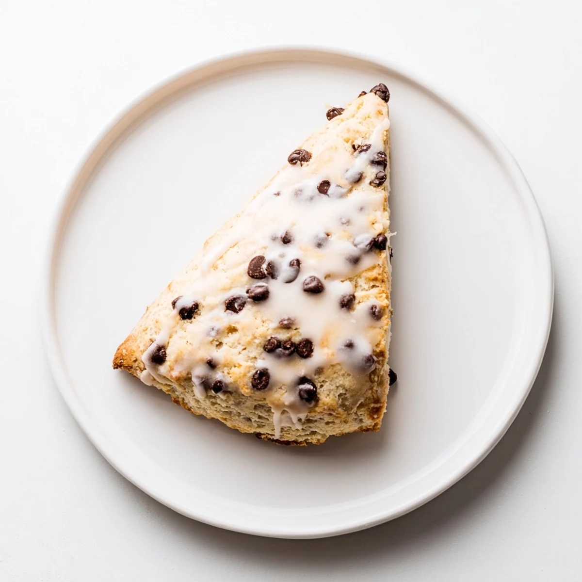 A warm Chocolate Chip Scones with Glaze drizzled with sweet vanilla icing, perfect for a cozy breakfast treat.  