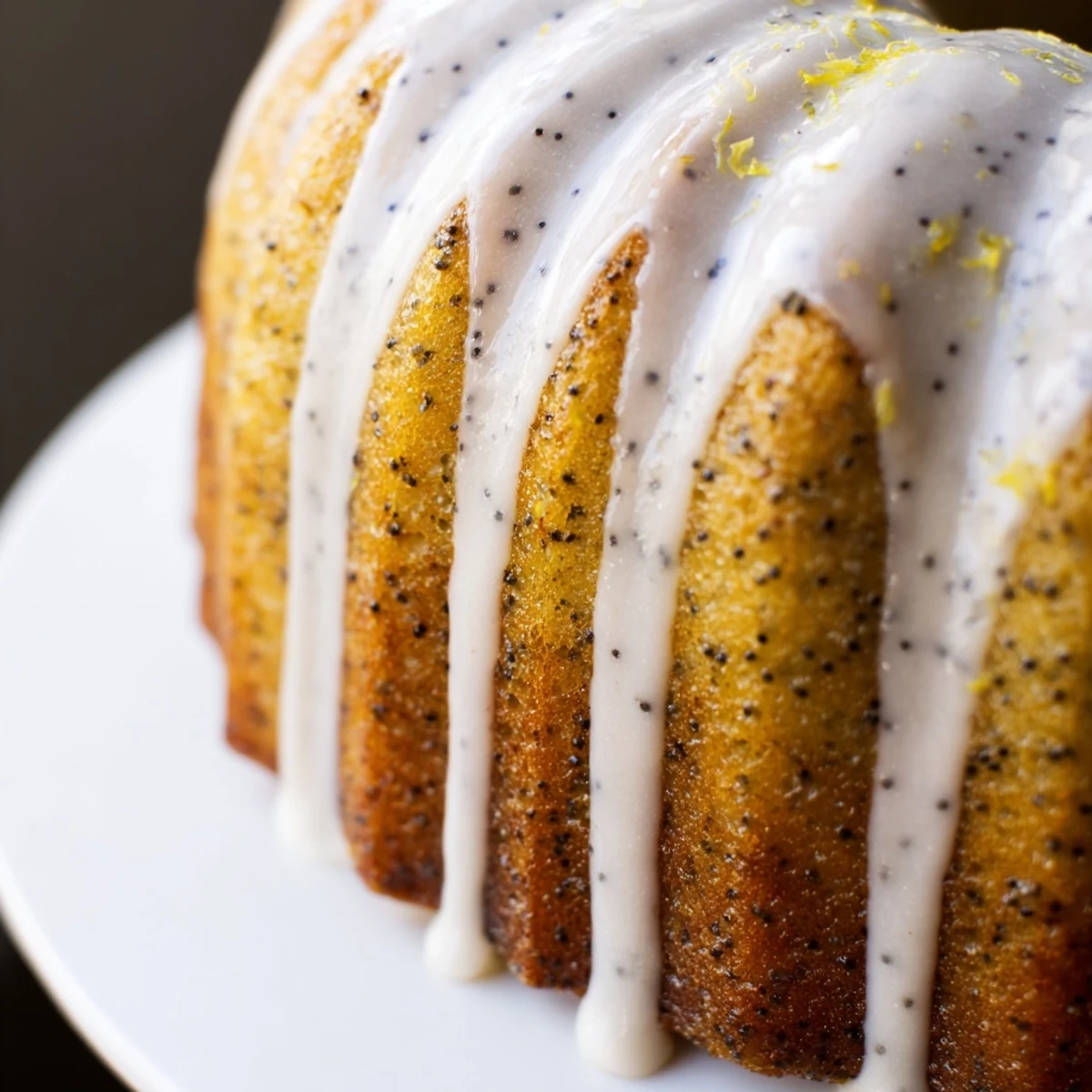 Sliced wedge of Lemon Poppy Seed Bundt Cake on a white plate, ready to serve with a hot cup of coffee.