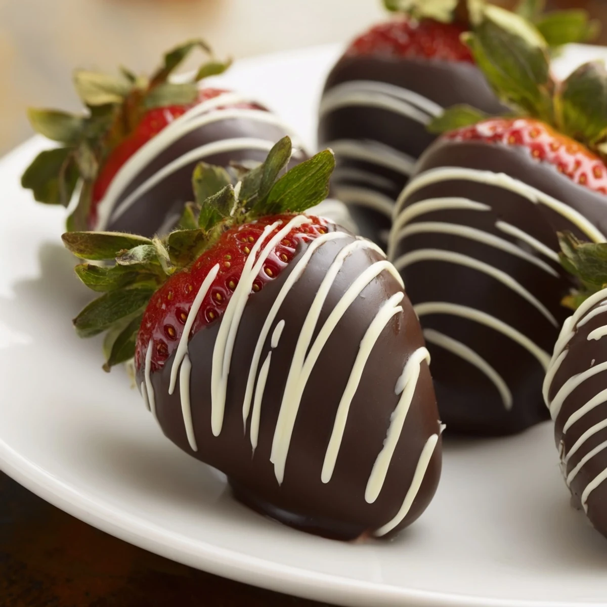 A close view of dark chocolate coated strawberries finished with white chocolate lines, ideal for romantic date nights.  