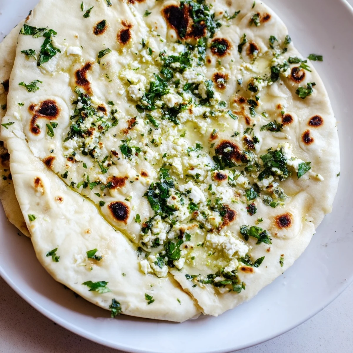 A golden, bubbly Cottage Cheese Garlic Naan fresh from a hot cast-iron skillet, brushed with melted butter and herbs.