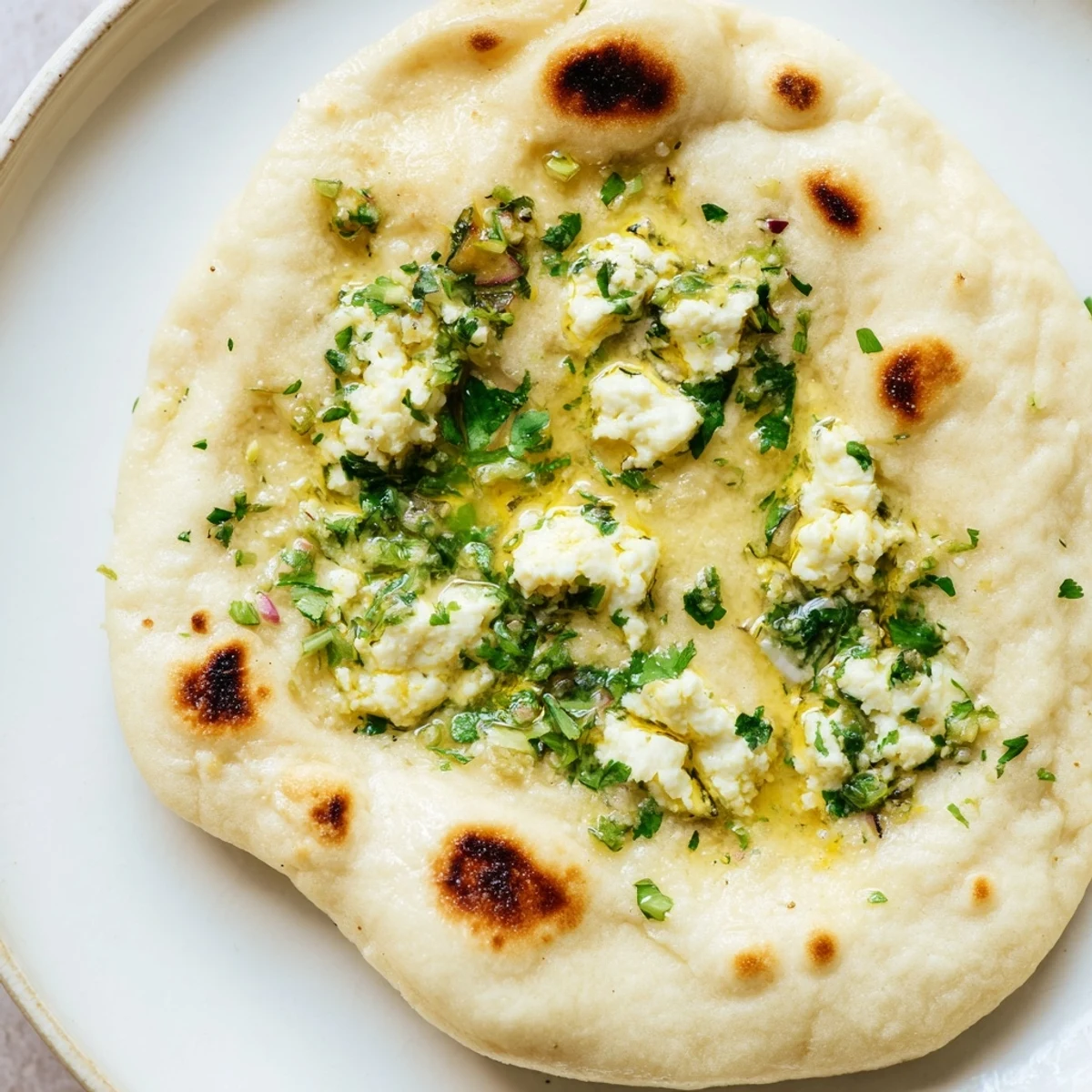 Close-up of soft, pillowy Cottage Cheese Garlic Naan with a visible cheesy filling and flecks of fresh green cilantro.