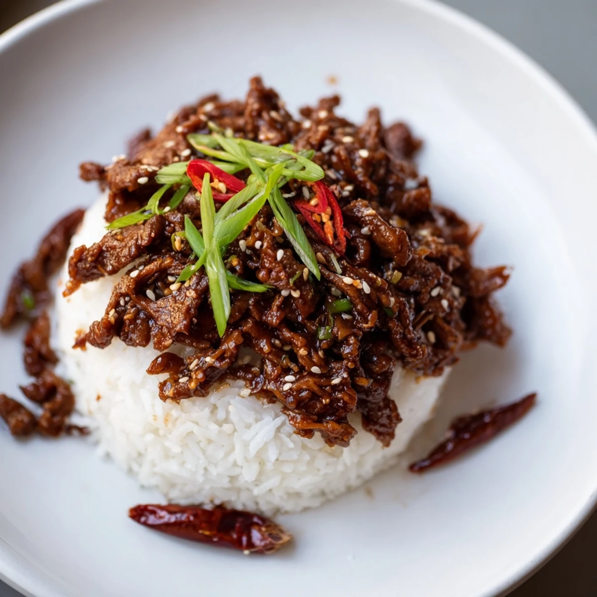 A steaming bowl of Slow Cooker Korean beef piled on jasmine rice, with kimchi and lettuce wraps nearby.