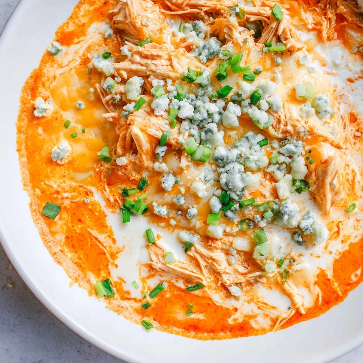 Golden, bubbly Keto Buffalo Chicken Dip baked in a dish with crunchy celery sticks for dipping.