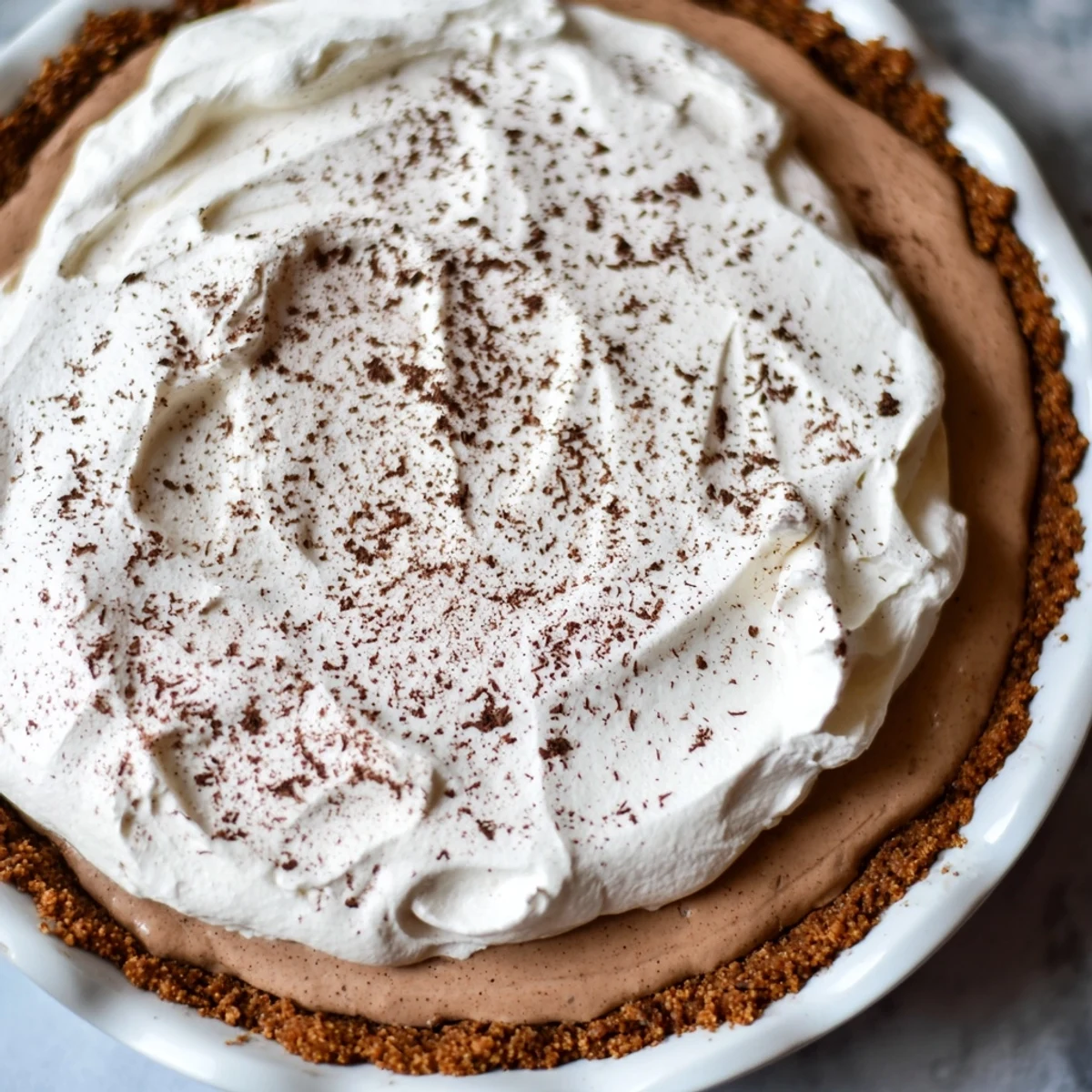 A chilled slice of Keto Cold Brew Coffee Pie reveals a smooth coffee-infused filling and crisp nutty crust on a rustic plate.