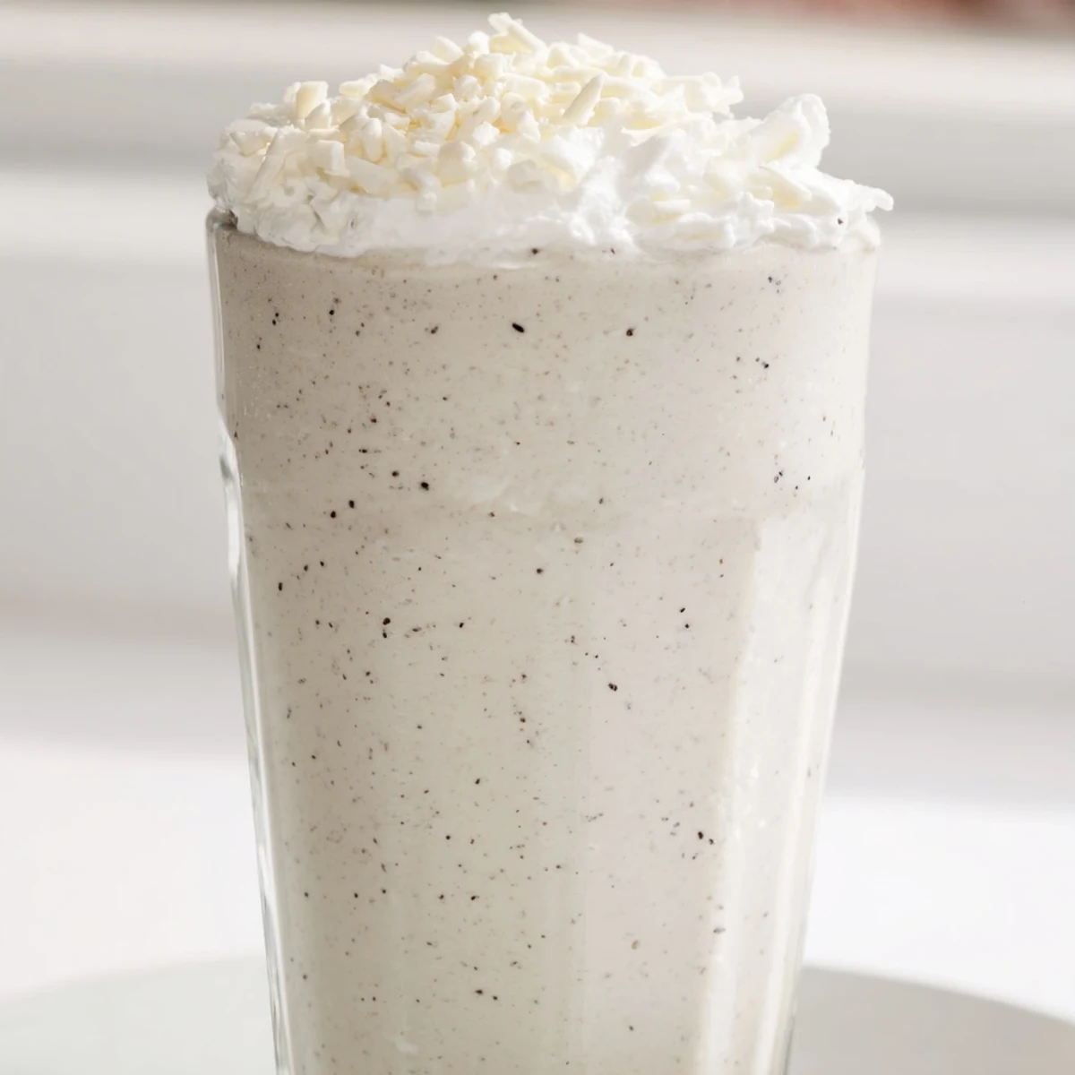 Creamy homemade Vanilla Bean Frappuccino topped with whipped cream in a tall glass.