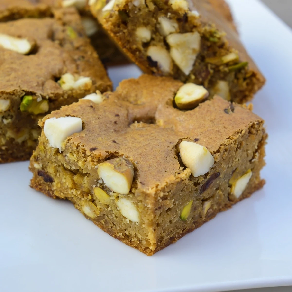 A close-up of chewy Pistachio Blondies, showing melted white chocolate chips and nutty pistachio pieces inside.