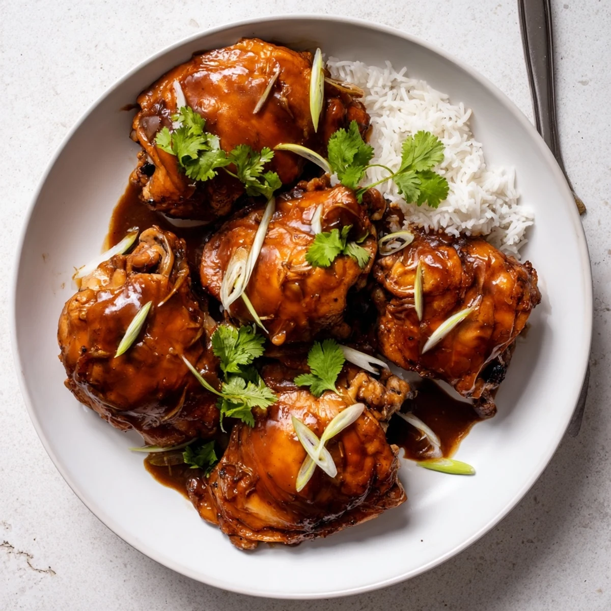 Tender chicken thighs glistening in caramel sauce for Ga Kho served over jasmine rice.
