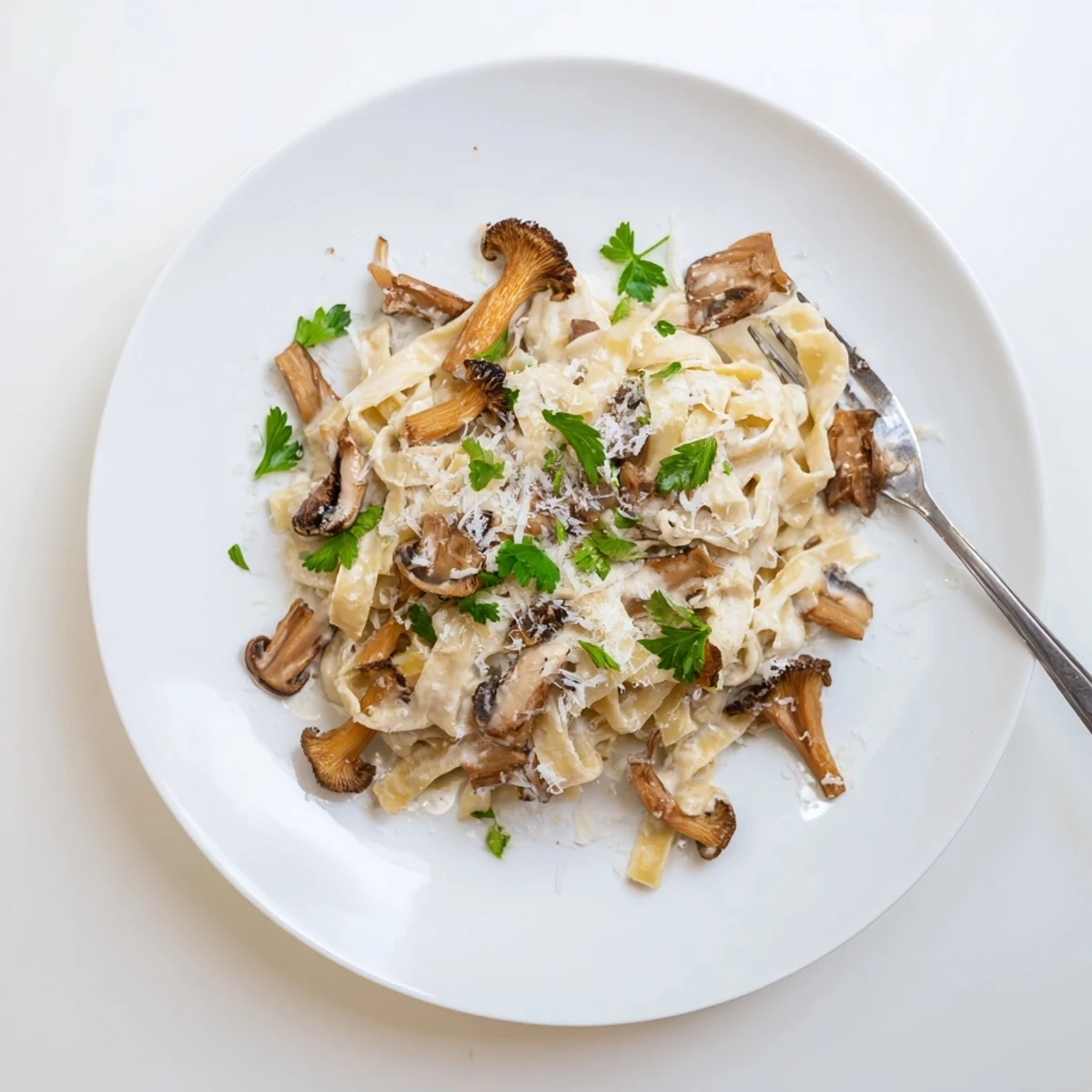 A close-up of sautéed mushrooms and tagliatelle coated in velvety cream sauce, topped with grated Parmesan and truffle oil.