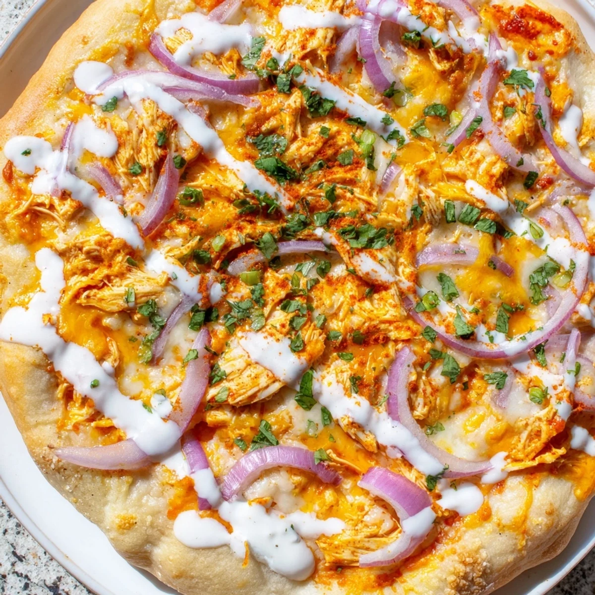 Freshly baked Bold Buffalo Chicken Pizza with melted mozzarella and cheddar cheese, topped with spicy buffalo chicken and sliced red onion.