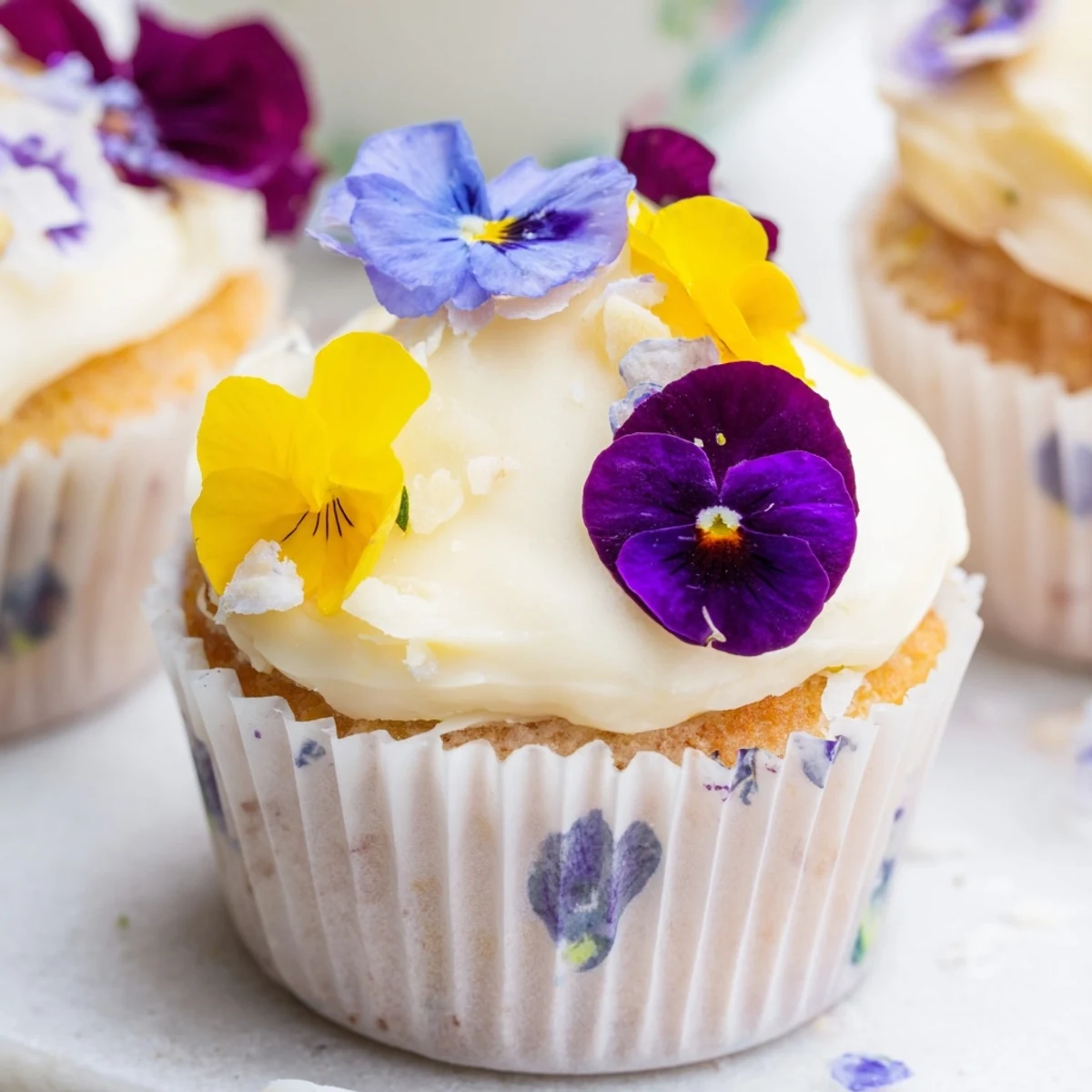Rustic Wild Flower Cupcakes on a wooden board, surrounded by fresh wildflowers and tea for a charming garden party.