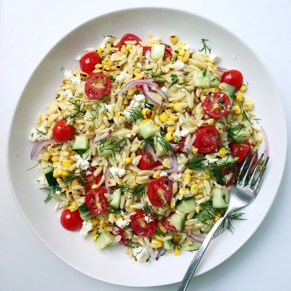 A close-up of the vibrant Grilled Corn Orzo Salad with Scallion Dill Dressing, featuring charred kernels and creamy feta crumbles on a rustic wooden table.