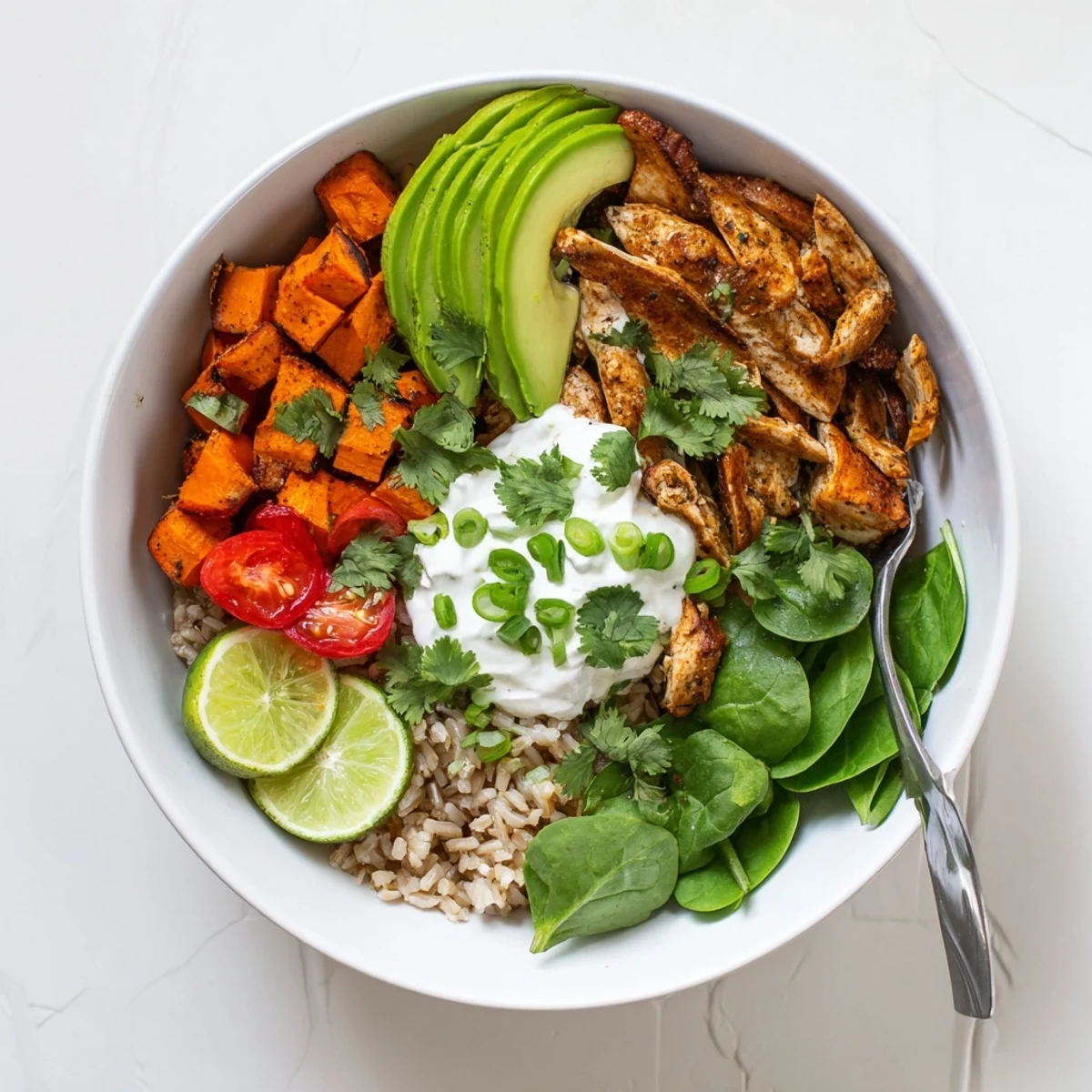 Freshly assembled Wholesome Chicken Sweet Potato Rice Bowl topped with cilantro and Greek yogurt, ready to serve warm.
