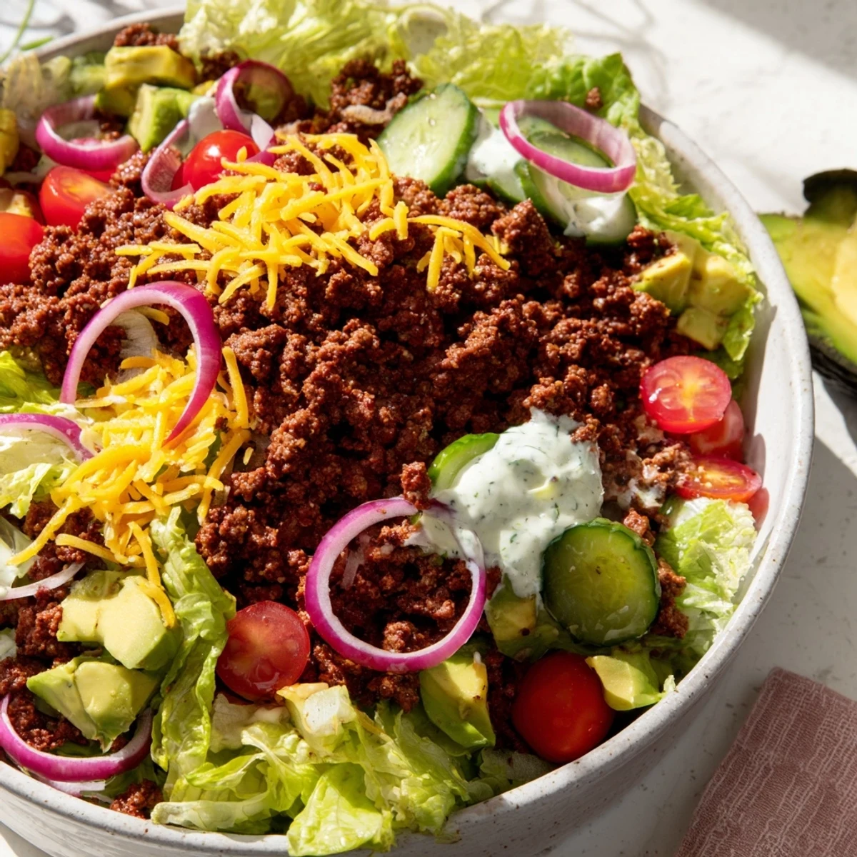 Savory Burger Bowls topped with cherry tomatoes, pickles, and red onion, ready to serve for a low-carb dinner.