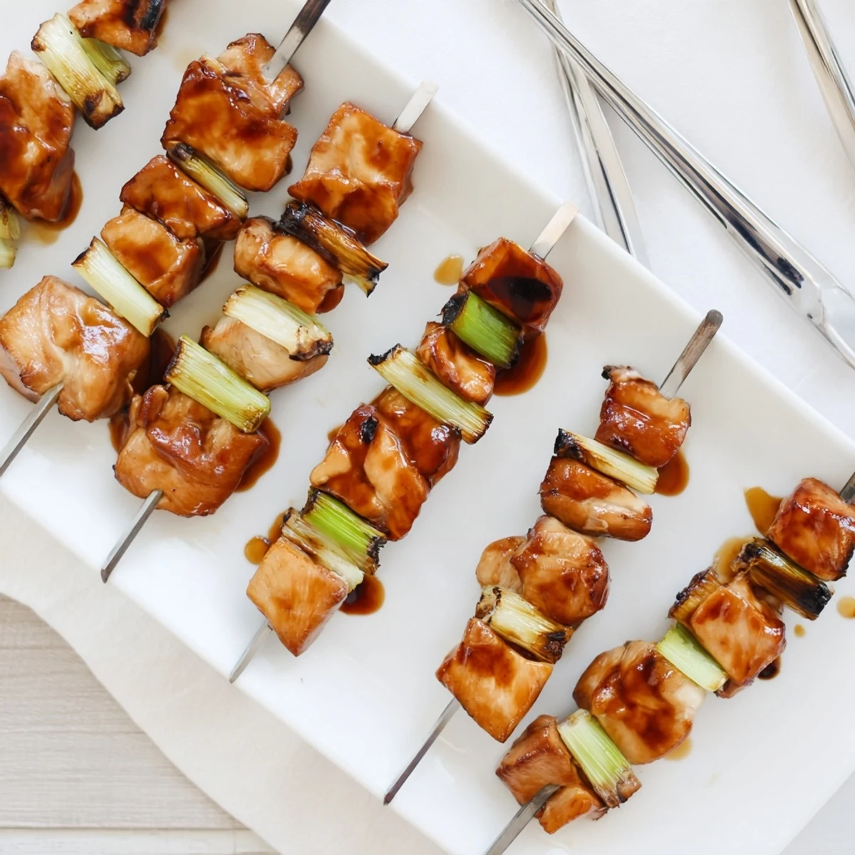 Close-up of Japanese Chicken Yakitori pieces charred perfectly, brushed with glossy soy-based sauce on bamboo sticks.