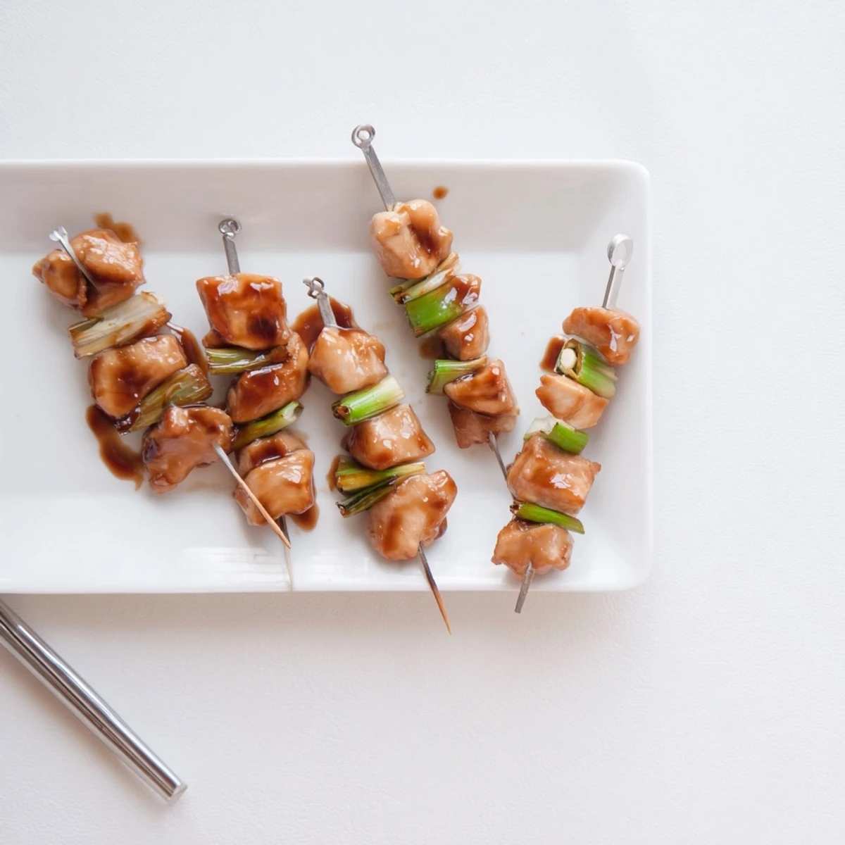Savory Japanese Chicken Yakitori plated as an appetizer, alongside cold sake and grilled vegetables for dipping.