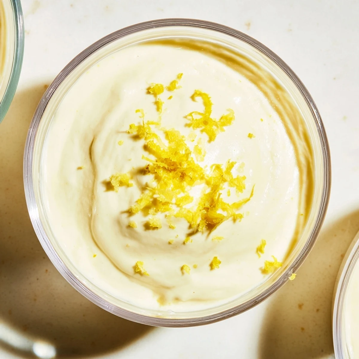 Creamy lemon cheesecake mousse topped with fresh berries and graham cracker crumbs in glass serving bowls