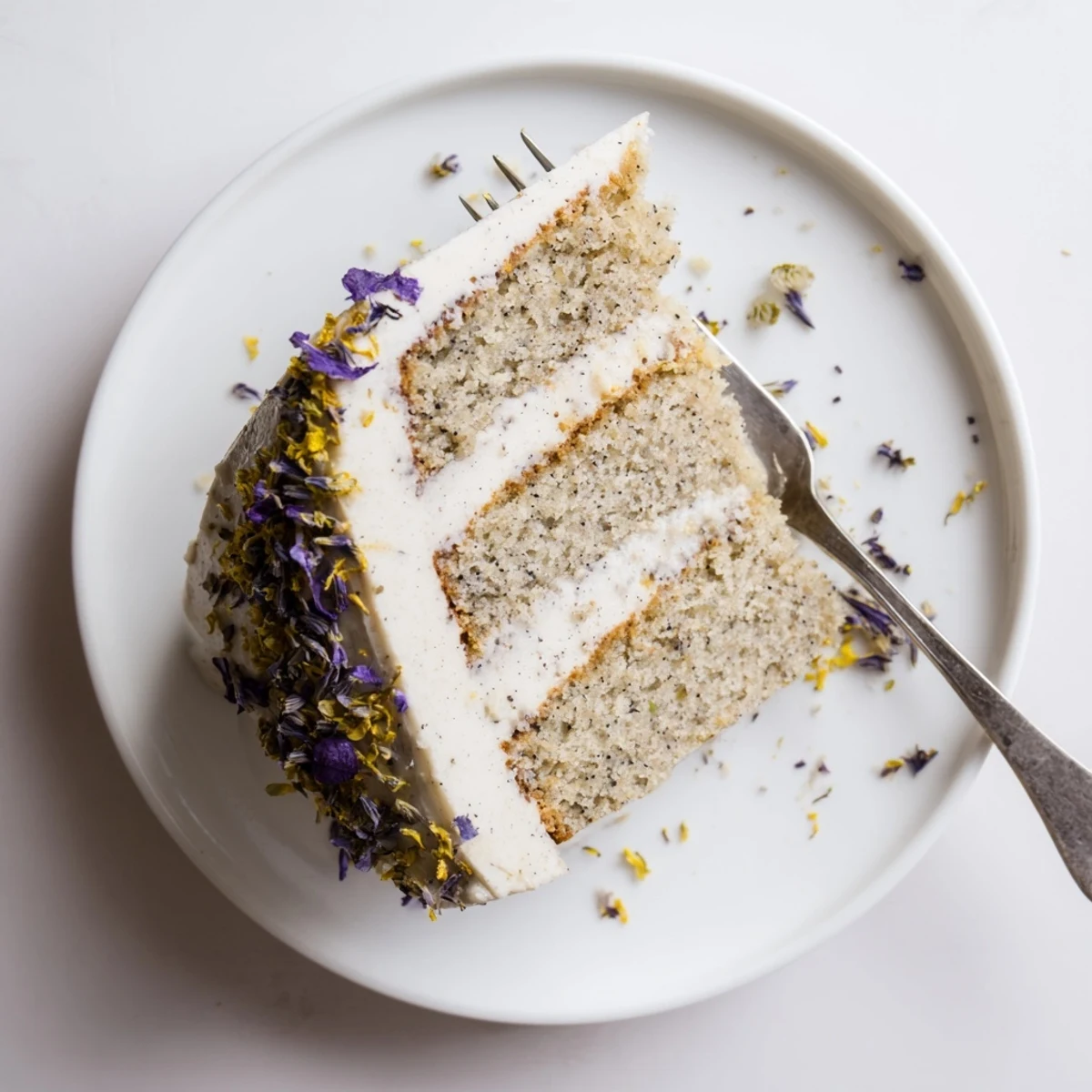 Slice of floral London Fog cake revealing tender vanilla bean frosting between tea-spiced layers