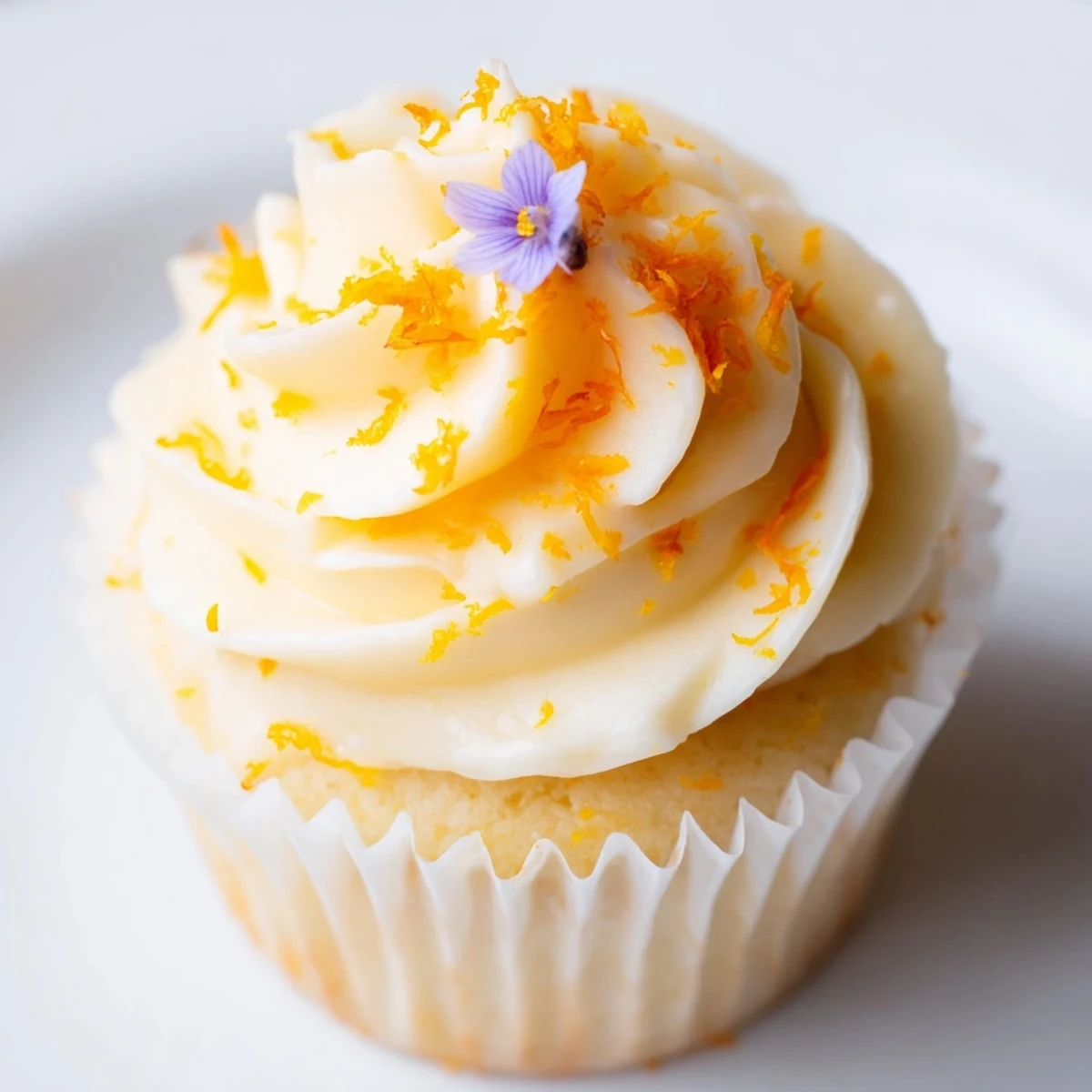 Golden orange blossom cupcakes topped with fluffy citrus frosting and fresh orange zest garnish