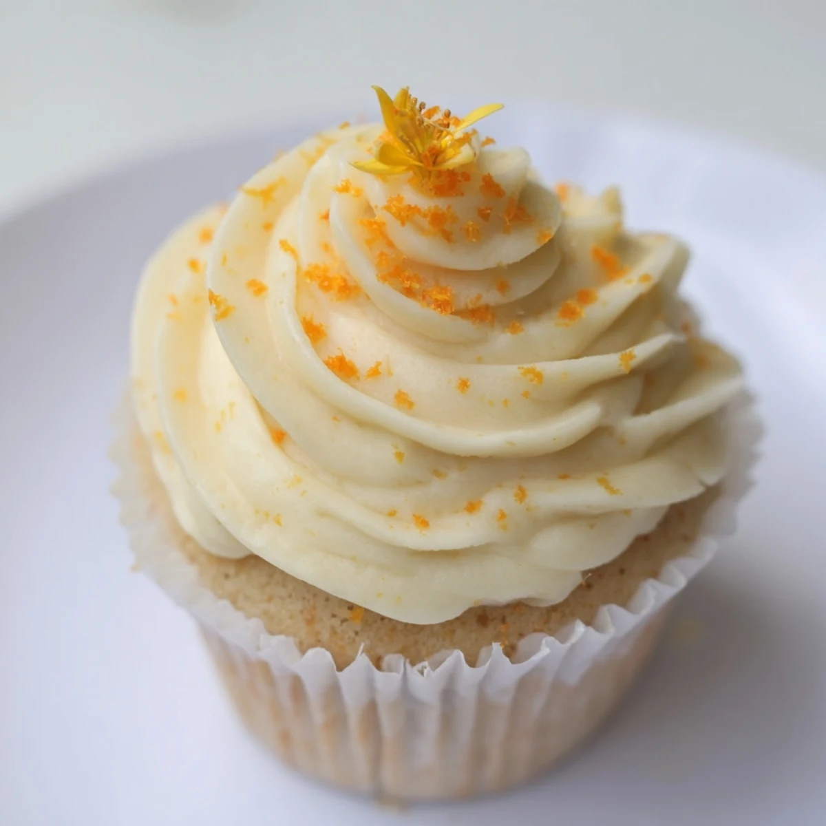 Spring dessert featuring light orange blossom cupcakes with tangy citrus frosting and edible flowers