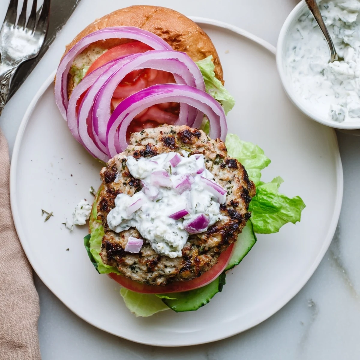 Homemade Greek chicken burgers with feta, herbs, and cucumber tzatziki sauce served in a toasted bun