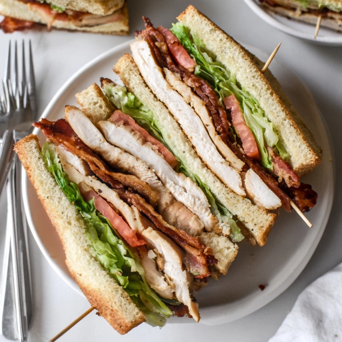 Triple-decker chicken club sandwich layered with fresh vegetables and creamy mayonnaise on toasted bread
