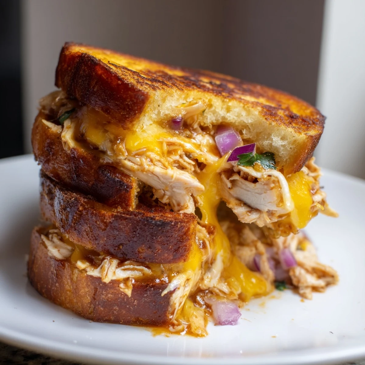Hot BBQ chicken grilled cheese oozing melted cheese between buttery crispy bread slices