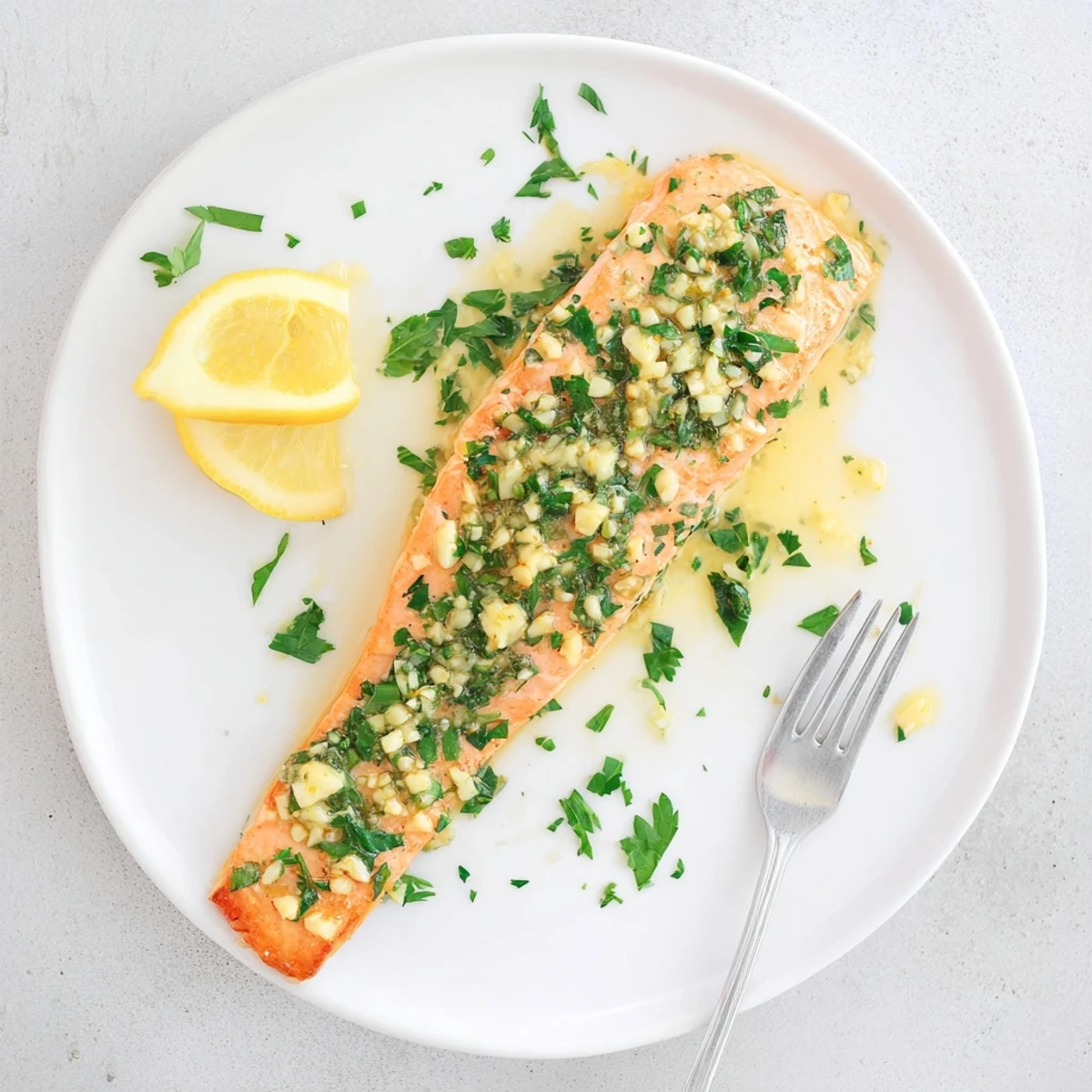 Golden baked salmon fillet glazed with melted garlic butter sauce and fresh parsley