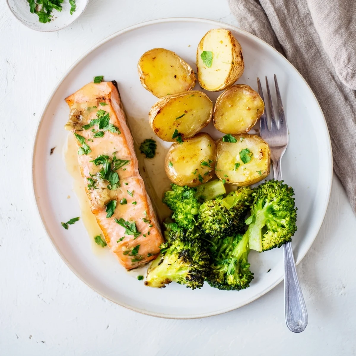 Juicy salmon pieces in creamy lemon butter sauce arranged with roasted baby potatoes and broccoli on a rustic wooden serving board