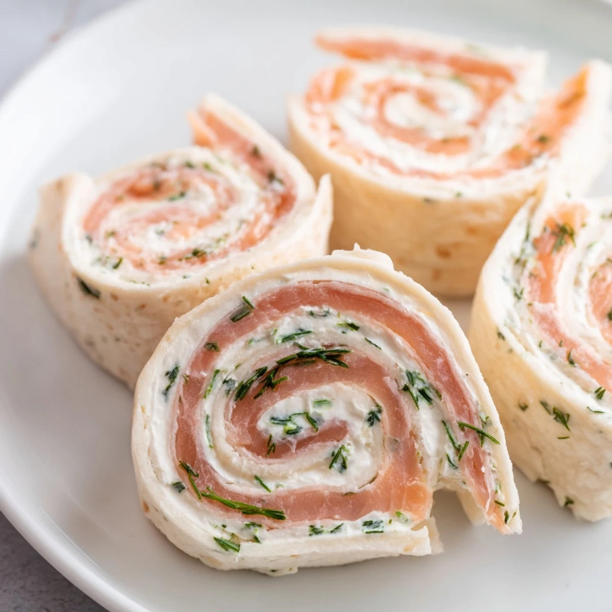 Close-up of smoked salmon pinwheels featuring creamy dill cheese filling and delicate green chive garnish