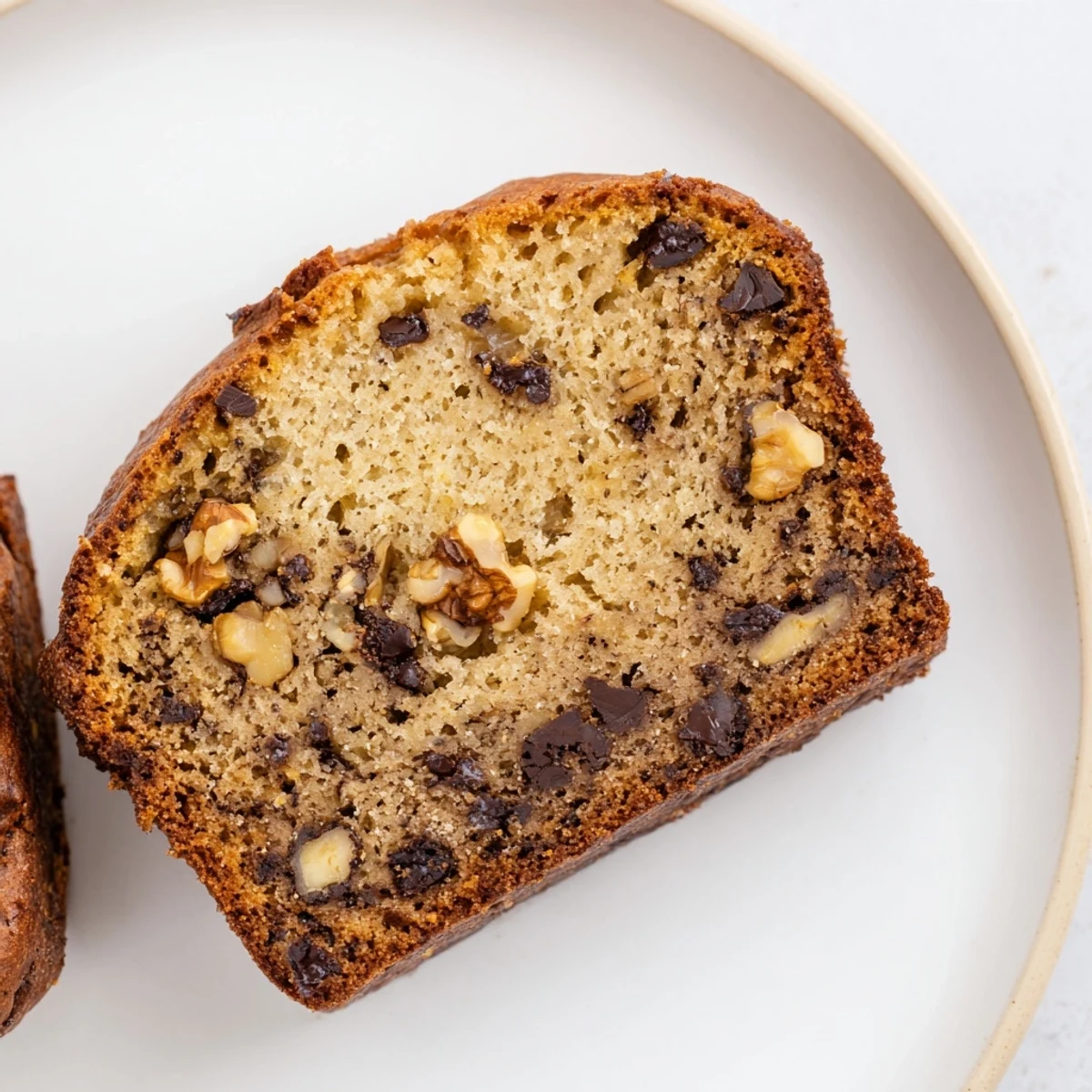 Golden brown super moist banana bread loaf with a tender crumb, sliced to reveal fluffy interior