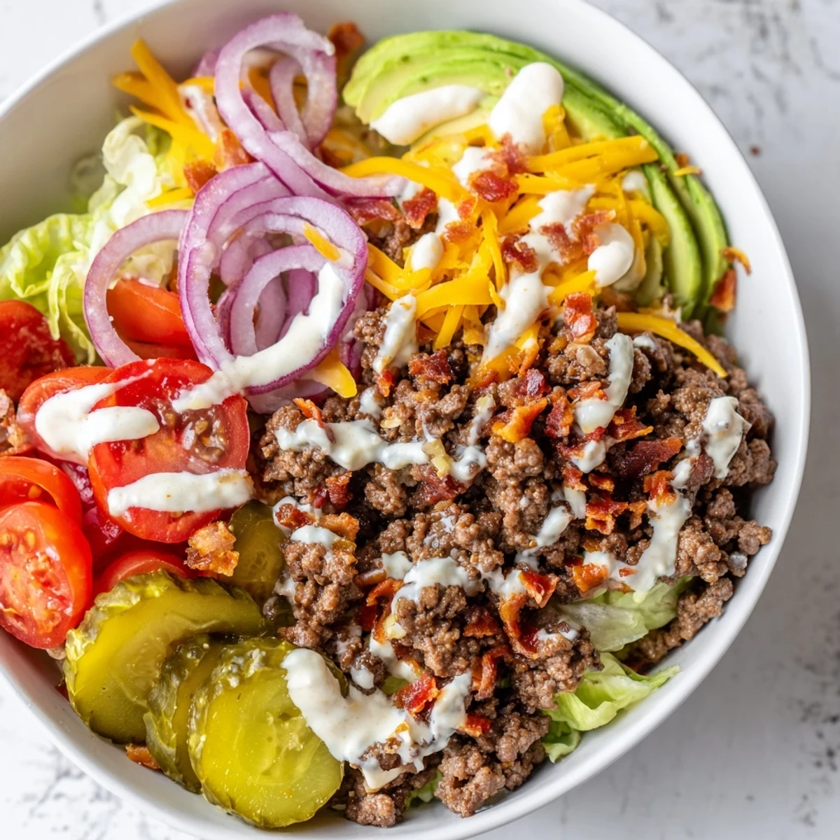 Low-carb burger bowls topped with melted cheddar, cherry tomatoes, pickles, and creamy homemade burger sauce.