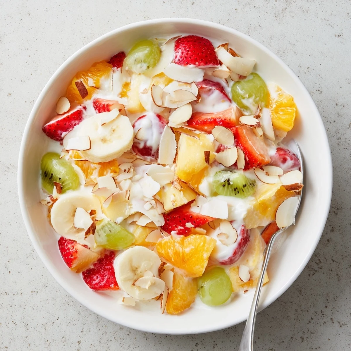 Colorful creamy fruit salad bowl featuring strawberries, grapes, and pineapple in sweet vanilla yogurt dressing