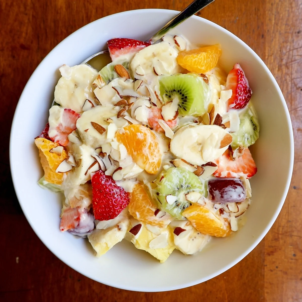 Luscious creamy fruit salad dessert with fresh berries and banana slices coated in tangy Greek yogurt sauce