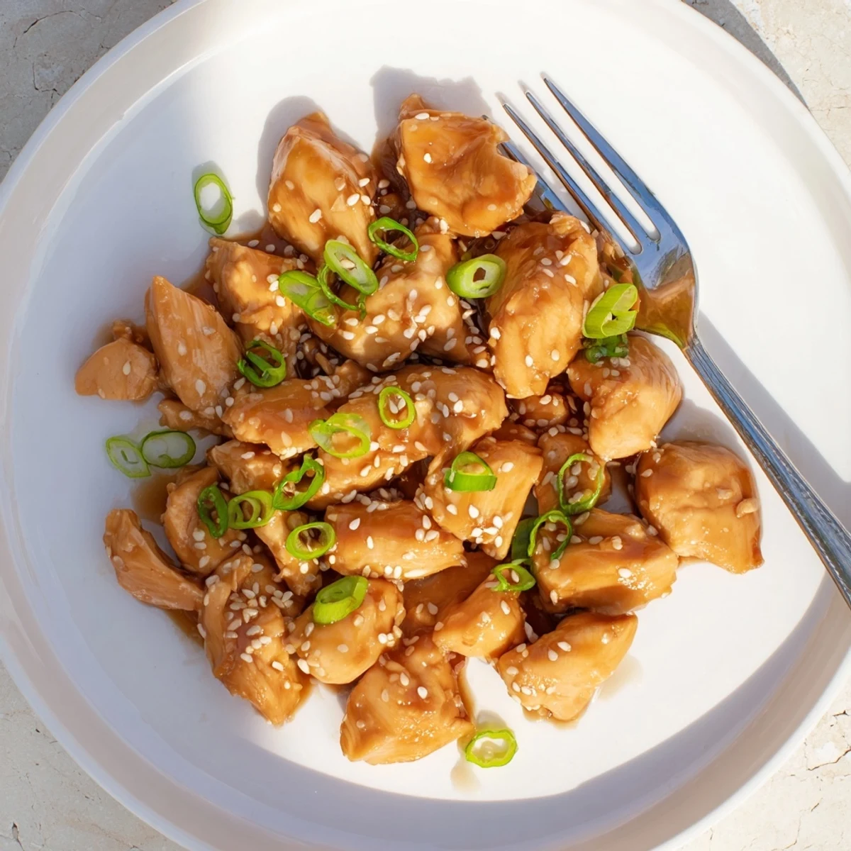 Tender slow-cooked chicken thighs glistening with sweet savory teriyaki glaze in a bowl
