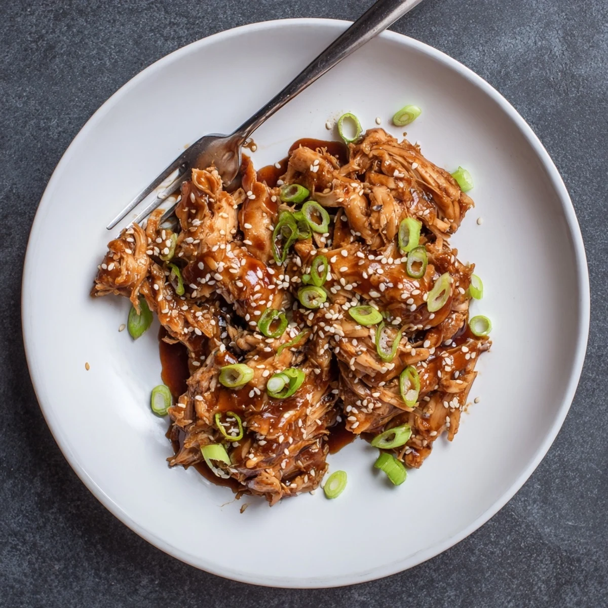 Shredded teriyaki chicken drizzled with thick glossy sauce over steaming white rice