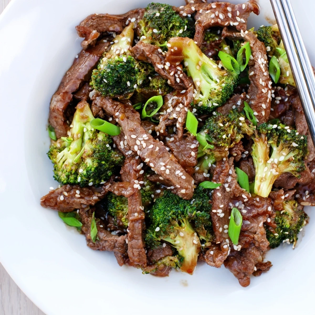 Garnished bowl of Instant Pot beef and broccoli over steamed white rice with sesame seeds