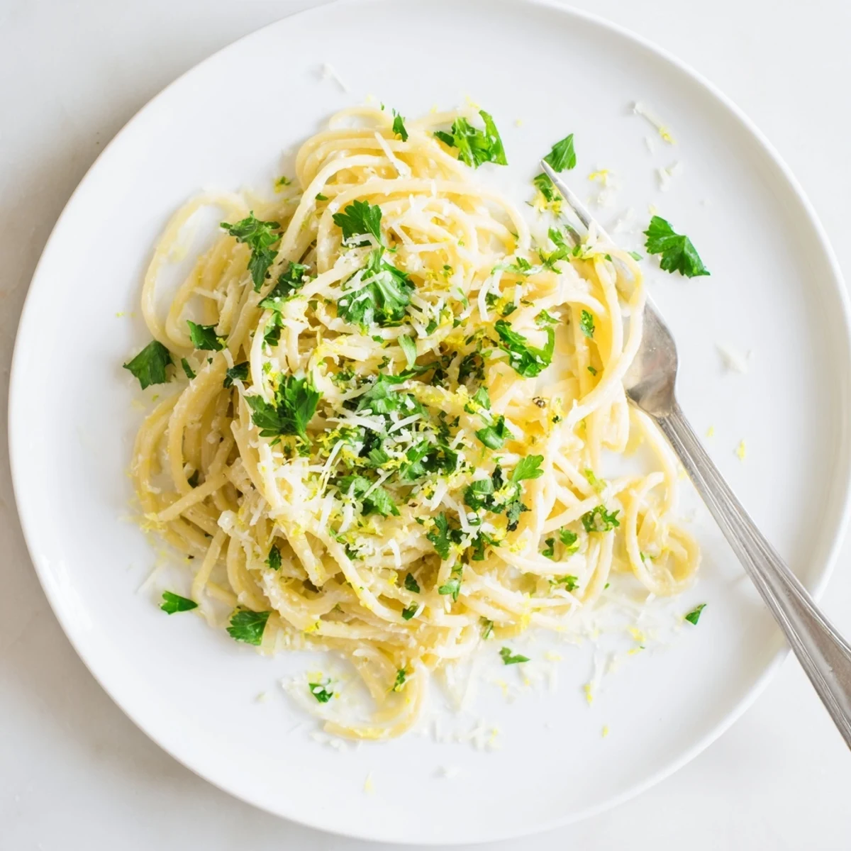 Steaming plate of one pot garlic butter pasta garnished with lemon zest and herbs