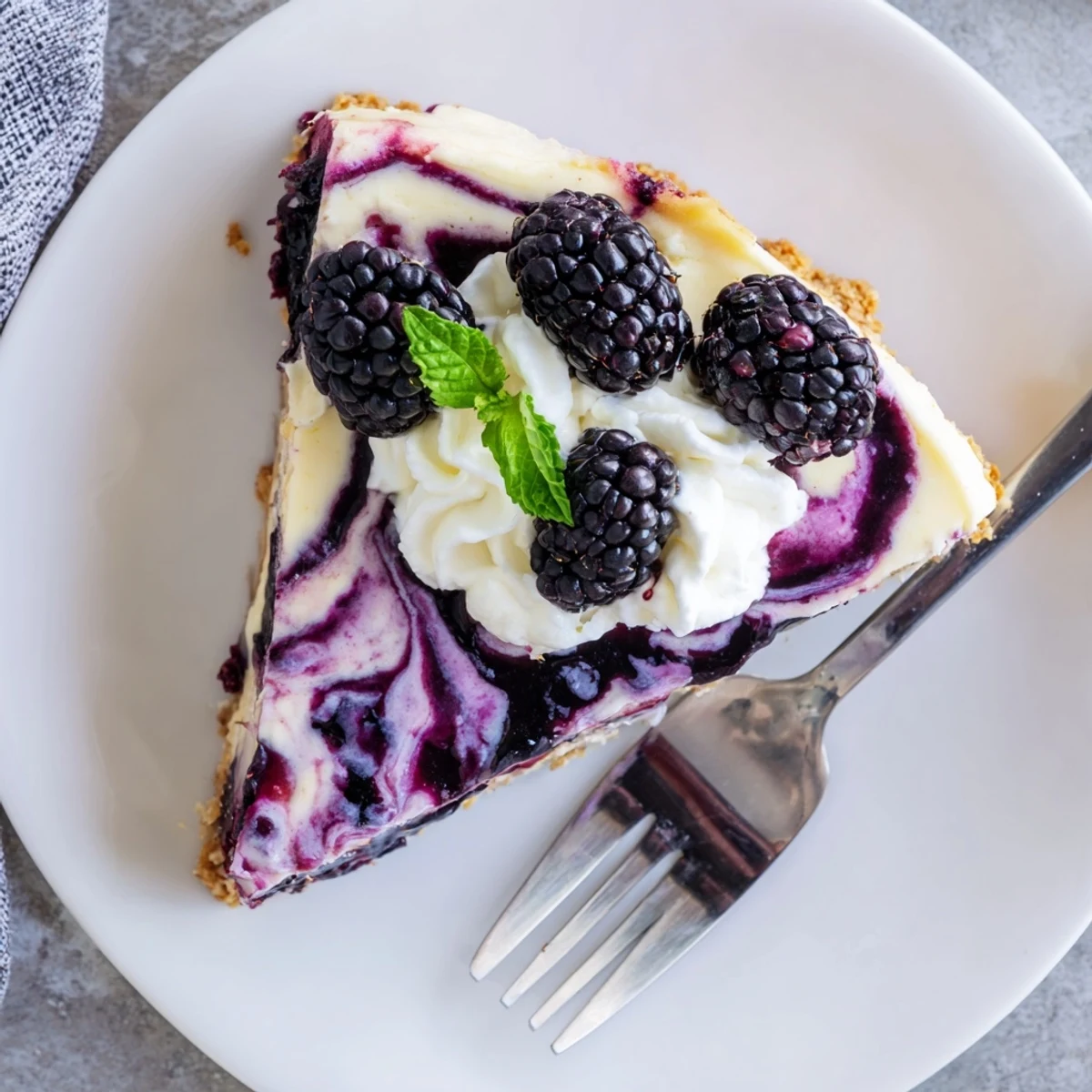 Creamy Blackberry Bliss Cheesecake with vibrant purple swirls on golden graham cracker crust