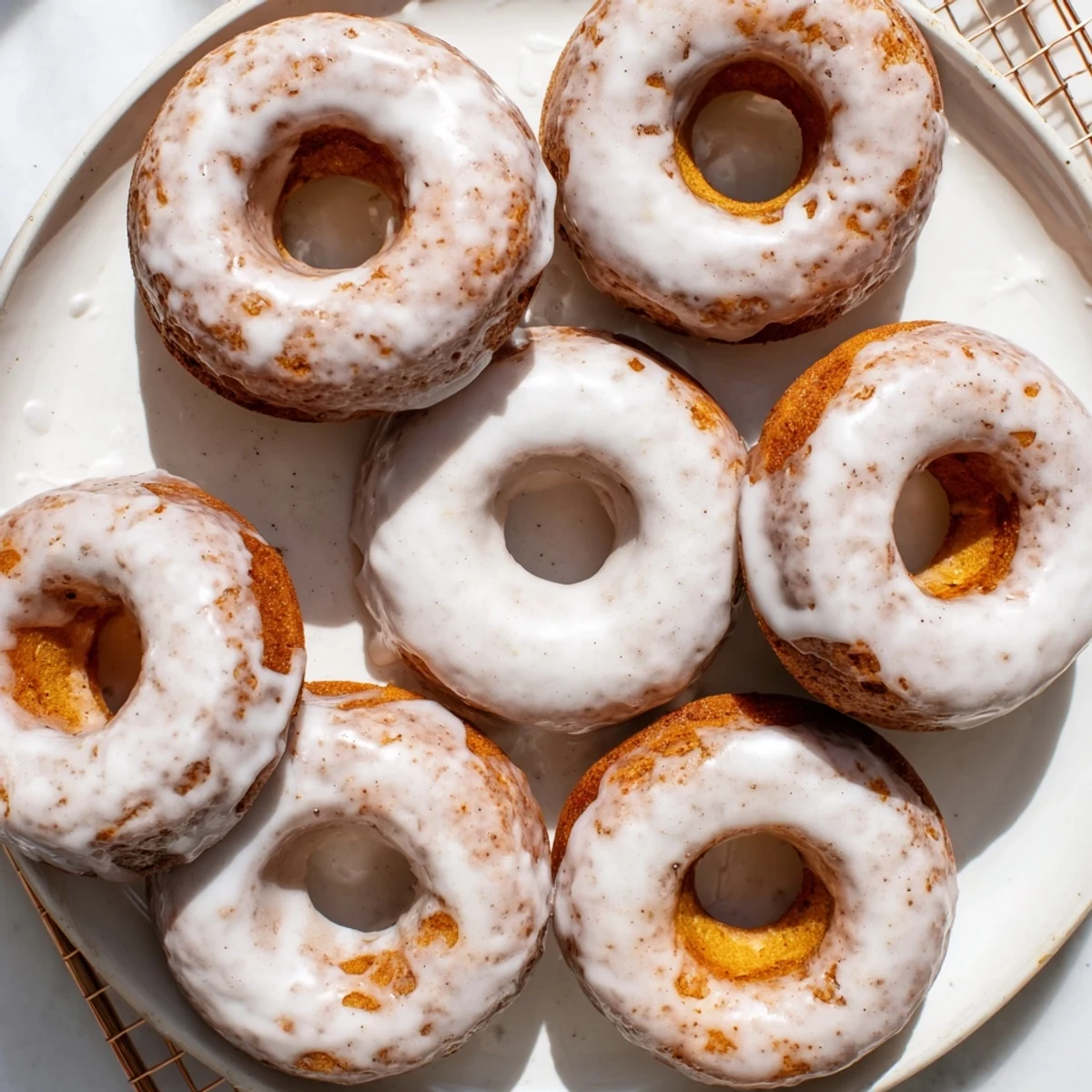 Freshly glazed Greek yogurt cake donuts sprinkled with colorful toppings on a white plate