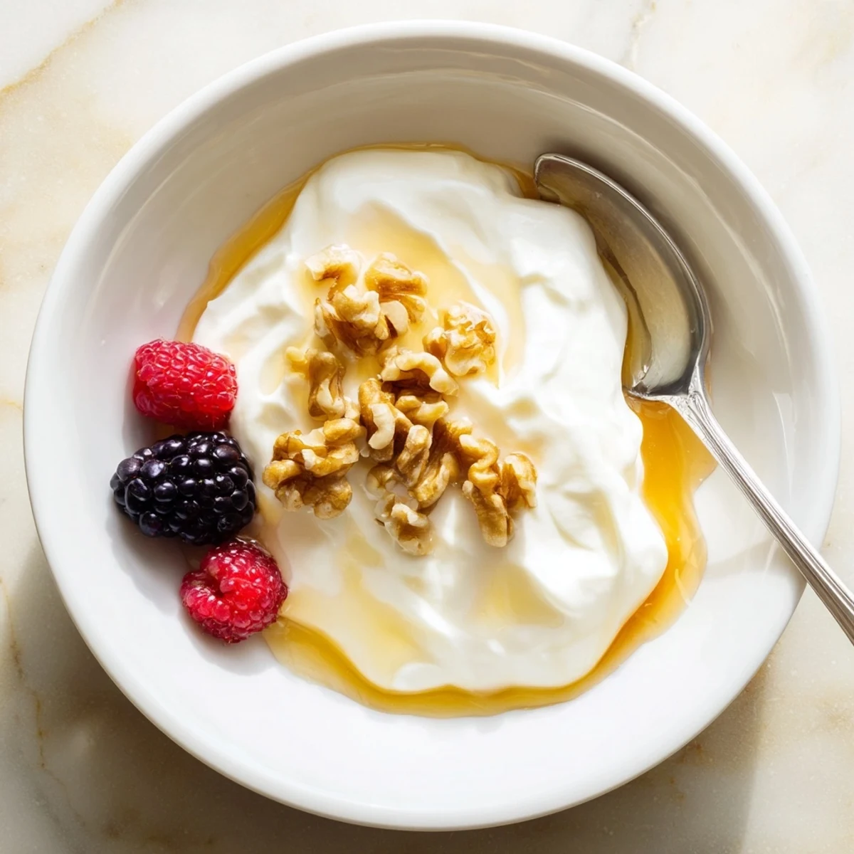 Creamy homemade Greek yogurt topped with fresh honey and crunchy walnuts in a white bowl