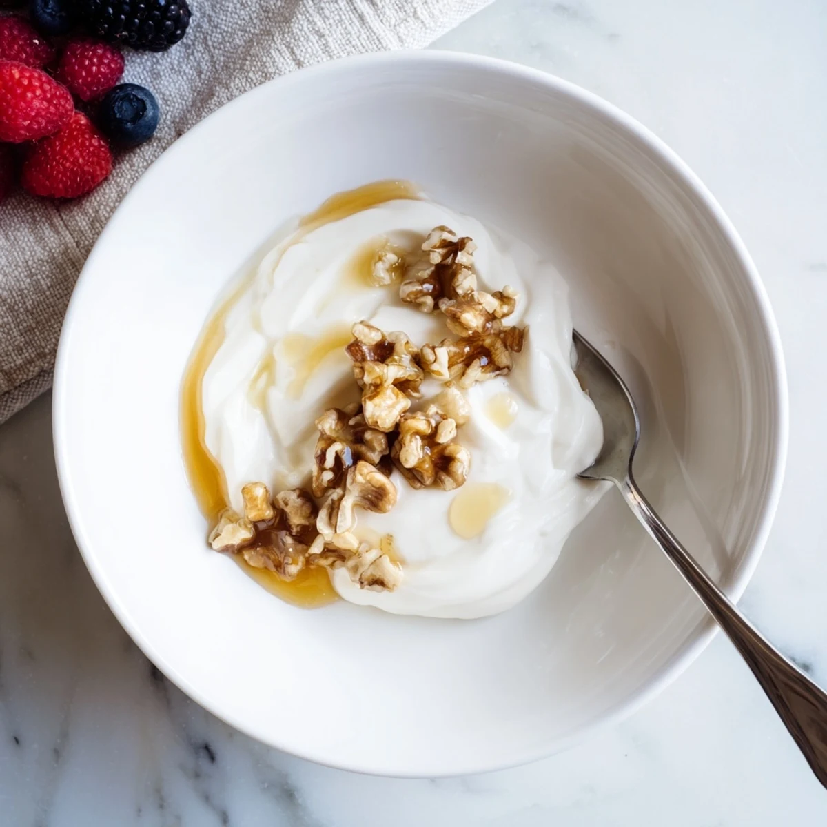 Thick strained Greek yogurt spoon onto a rustic wooden board with seasonal berries and mint